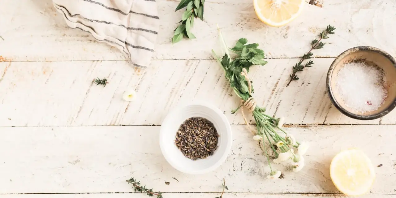 Zutaten für selbstgemachte Kosmetik: Lavendel, Kräuter, Zitrone und Salz auf Holzhintergrund.