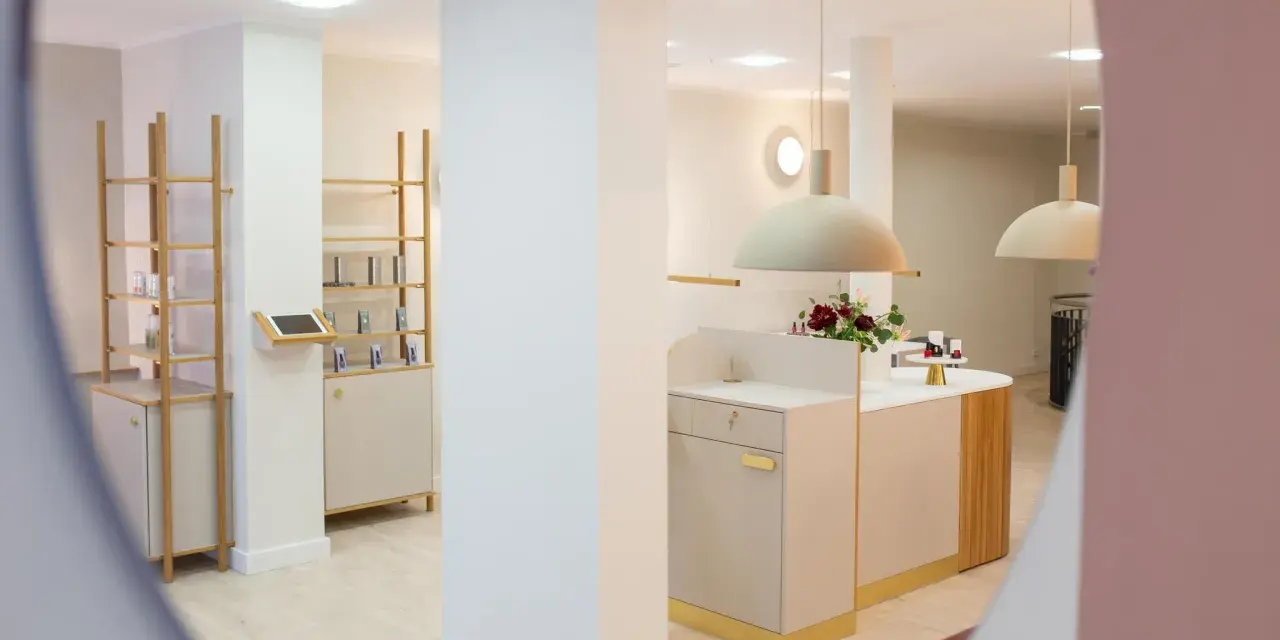 Helle, moderne Kosmetikboutique mit Regalen, Theke und Blumenarrangement.