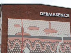 Gebäude mit Schriftzug DERMASENCE und einer Hautschichten-Grafik.