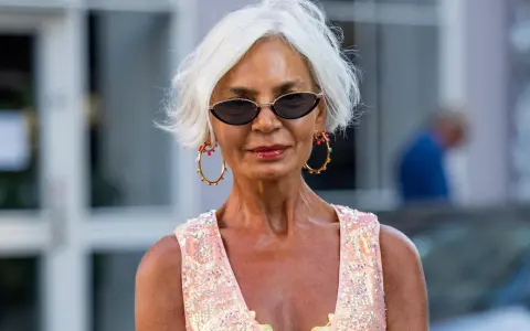 Frau mit weißem Kurzhaarschnitt, Sonnenbrille und auffälligem Schmuck.