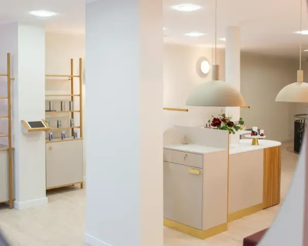 Helle, moderne Kosmetikboutique mit Regalen, Theke und Blumenarrangement.