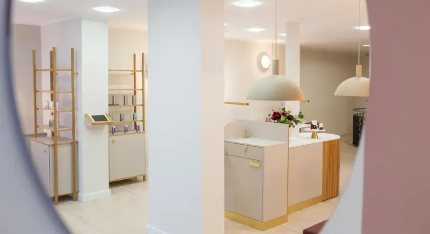 Helle, moderne Kosmetikboutique mit Regalen, Theke und Blumenarrangement.