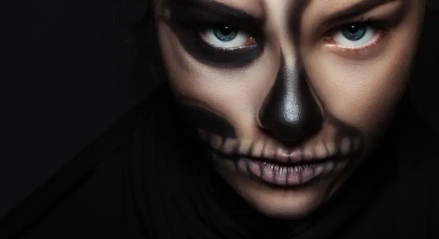 Frau mit Totenkopf-Halloween-Make-up, dunkler Hintergrund.